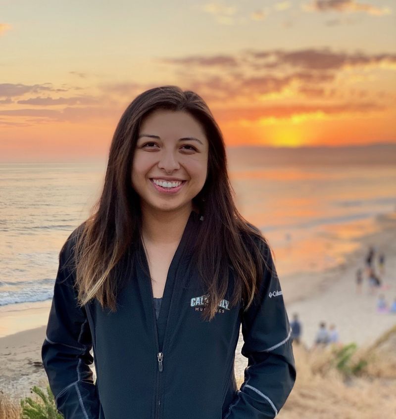 Leilani Molina smiling on a clifftop above the beach at sunset
