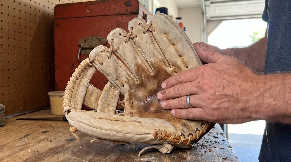 Hands rubbing oil into a worn baseball glove